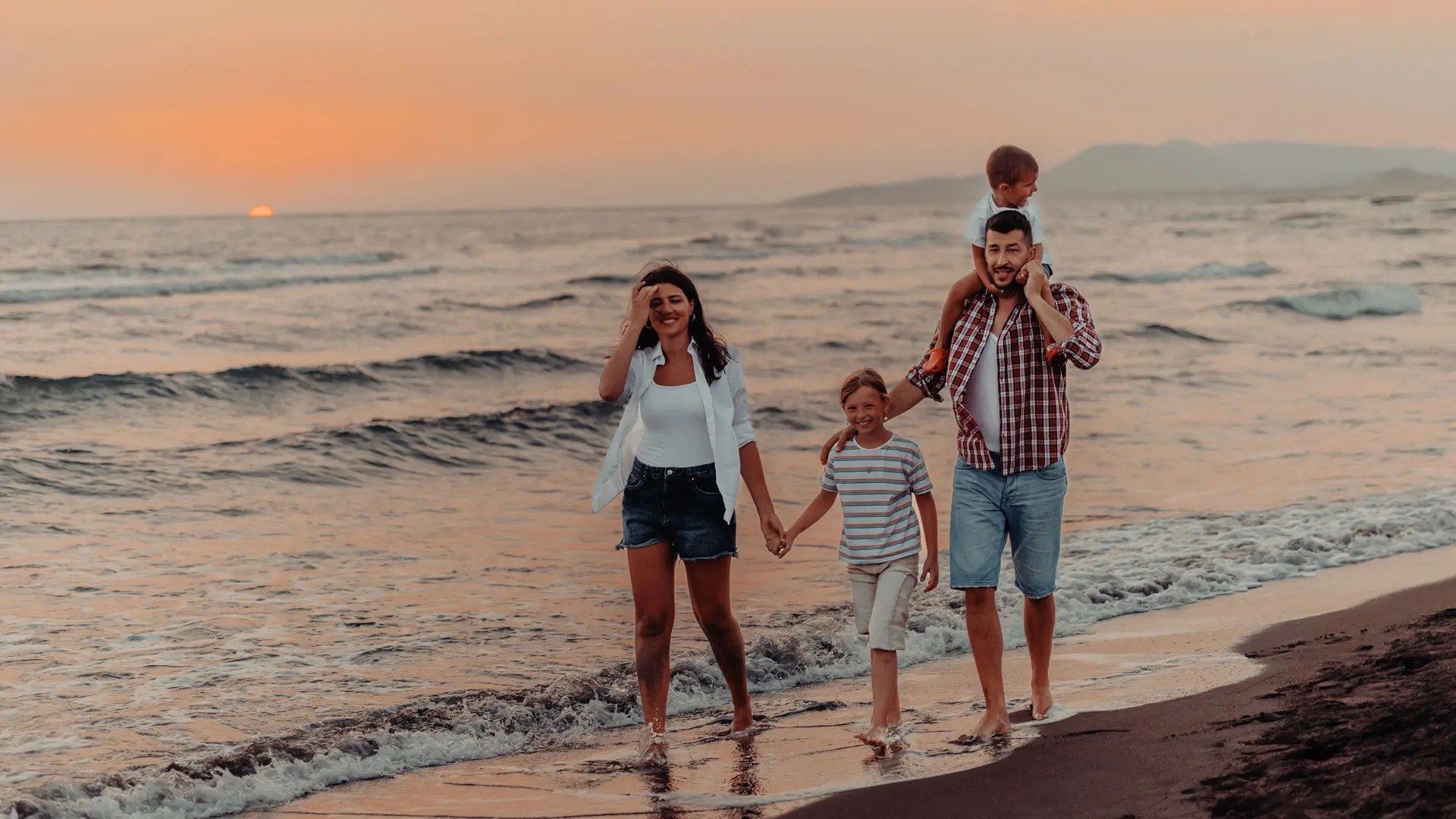 Familia disfrutando de un paseo en la playa al atardecer, simbolizando tranquilidad, bienestar y protección. La imagen representa el respaldo que brinda la Póliza Vida Grupo de Seguros Confianza, asegurando la estabilidad financiera y el futuro de los empleados y sus familias ante imprevistos.