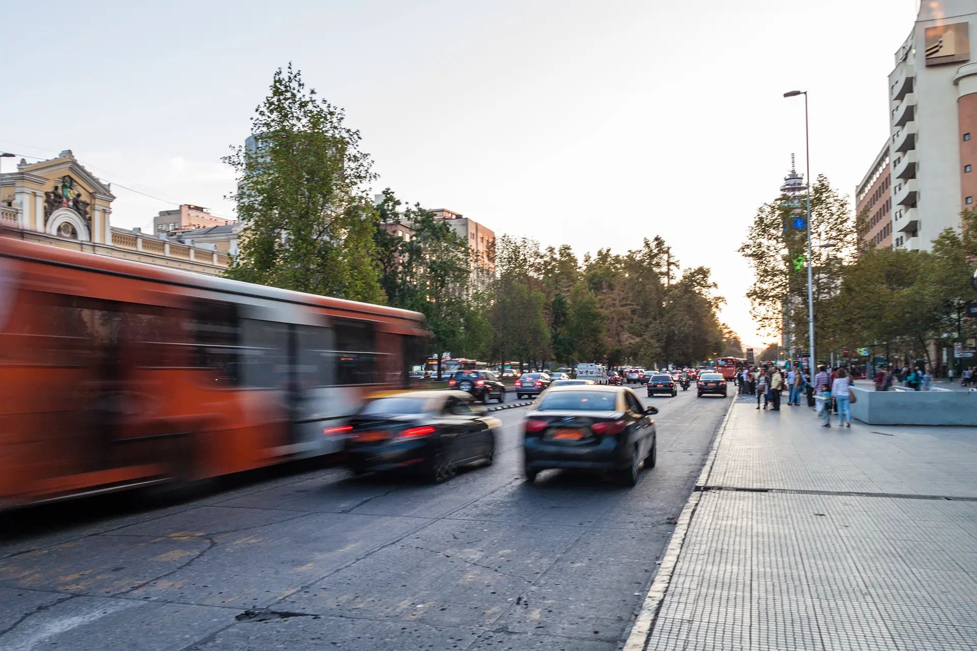 Tráfico urbano con buses y vehículos en movimiento al atardecer, representando la movilidad en la ciudad. La imagen acompaña una advertencia indicando que el SOAT no hace parte de los productos de Seguros Confianza.
