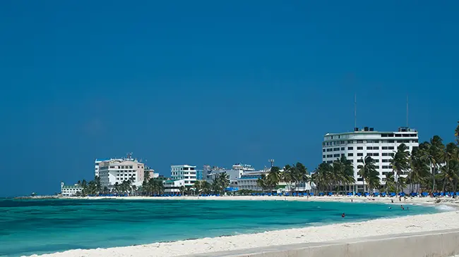 Vista panorámica de San Andrés, Colombia, con sus playas de arena blanca y edificios turísticos frente al mar Caribe. La imagen representa la presencia de Seguros Confianza en grandes proyectos de infraestructura, respaldando el desarrollo y la seguridad empresarial en la región.
