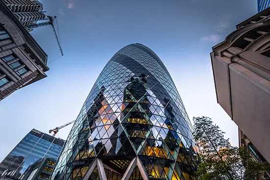 Vista desde abajo del icónico edificio The Gherkin en Londres, reflejando modernidad y solidez corporativa. La imagen representa la conexión de Seguros Confianza con Swiss Re Corporate Solutions, destacando su respaldo global, innovación y compromiso con la excelencia en seguros empresariales.