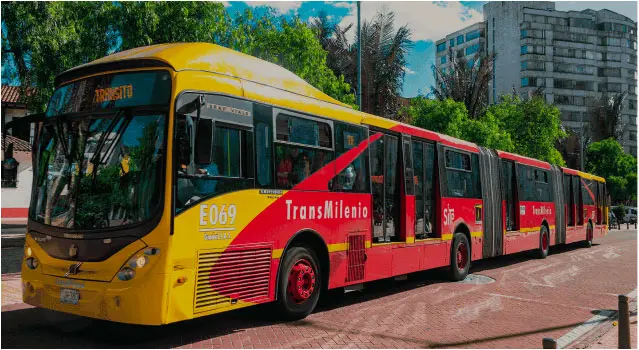 Autobús articulado de TransMilenio en Bogotá, parte del sistema de transporte masivo de la ciudad. La imagen destaca la participación de Seguros Confianza en grandes proyectos de infraestructura, brindando respaldo y seguridad en la obra civil de TransMilenio para garantizar su desarrollo y operación eficiente.